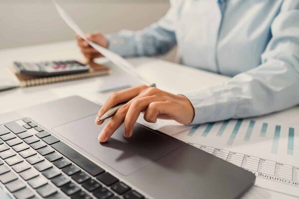 Woman accountant use calculator and computer with holding pen on